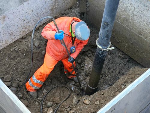 Construction worker using hydro vacuum to safely expose utilities