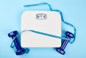 A scale with weights to either side of it and a measuring tape draped over it